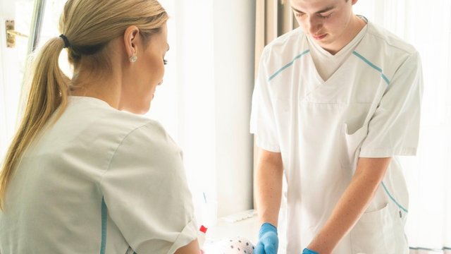 Zwei Pflegefachpersonen in weißer Dienstkleidung am Patientenbett